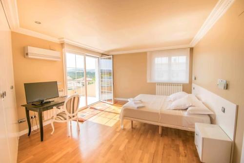 a bedroom with a bed and a desk with a computer at Ver Venir, acogedoras habitaciones con piscina in Garínoain