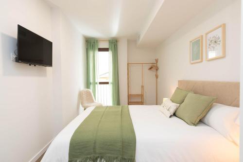 a white bedroom with a bed with a tv on the wall at Xena Abeto by BeValle in Panticosa