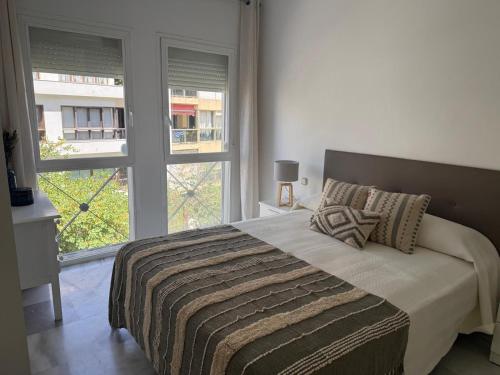 a bedroom with a large bed and two windows at Gilarez in Estepona