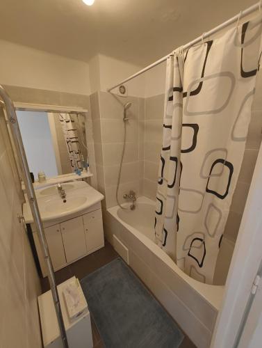 a bathroom with a tub and a sink and a shower curtain at T4 proche de la plage & du centre in LʼÎle-Rousse