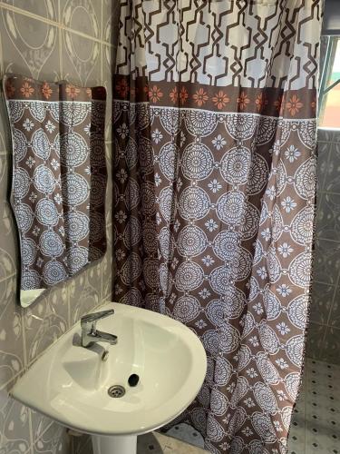 a bathroom with a sink and a shower curtain at FREDJACKSAIR BnB in Koforidua