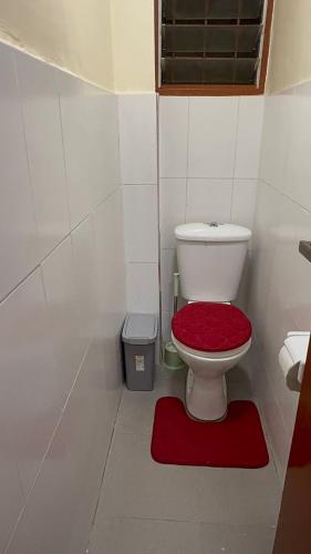 a bathroom with a toilet with a red seat at Affar homes in Kumasi