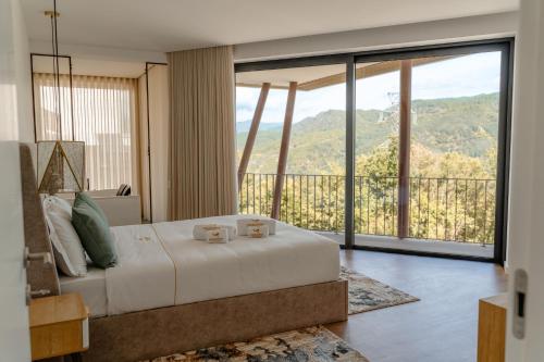 a bedroom with a bed and a balcony with mountains at Encosta de Louredo by Pousadela Village in Vieira do Minho