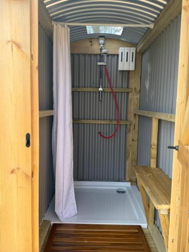 a shower in a tiny house with a red hose at Hill View Glamping Hut in Tregaron