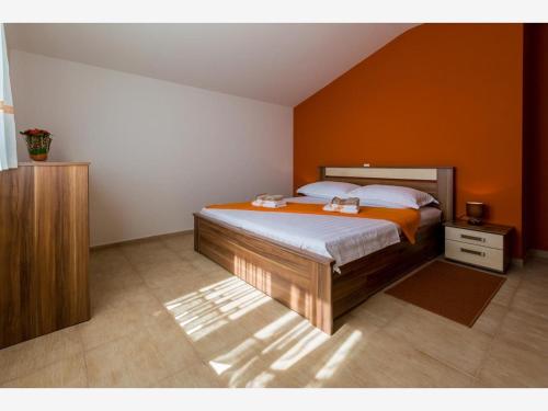 a bedroom with a large bed with an orange wall at Apartment Ivana in Crikvenica