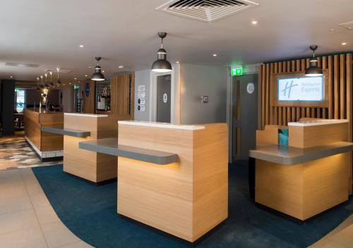 a lobby with wooden counters and a tv in the background at Holiday Inn Express Edinburgh - Leith Waterfront by IHG in Edinburgh