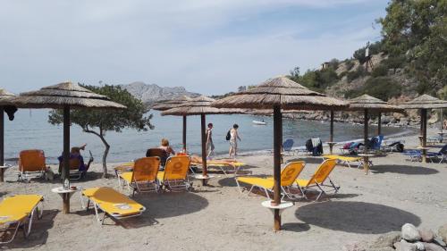 a group of chairs and umbrellas on a beach at To Spitaki House in Perdika