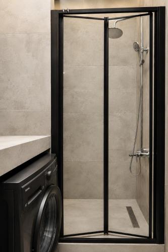 a shower with a glass door next to a washing machine at Mayak Bamboo Beach Apartments in Kobuleti