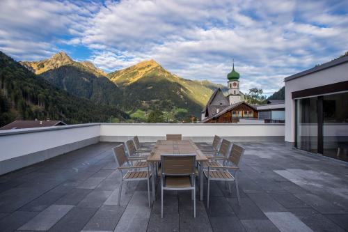 a table and chairs on a balcony with mountains at Appart Gastauer in Sankt Gallenkirch