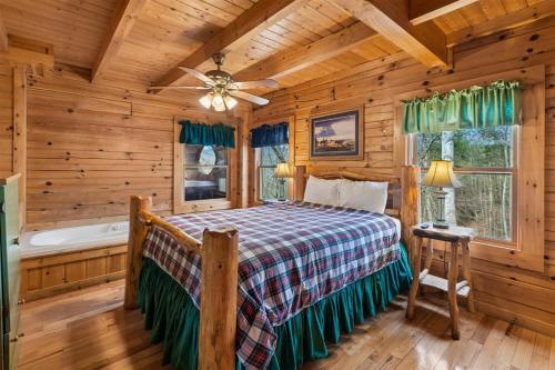a log cabin bedroom with a bed and a tub at Hoot n Hollar #31 by Venture Smoky Mountains in Sevierville