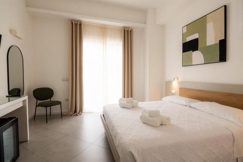 ein Schlafzimmer mit einem weißen Bett, auf dem zwei Handtücher liegen in der Unterkunft Sa Pasadina in Àrbatax