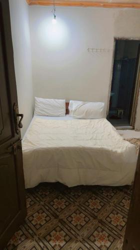 a bedroom with a bed with white sheets and a window at Ruby Bahrain Hotel in Mingāora