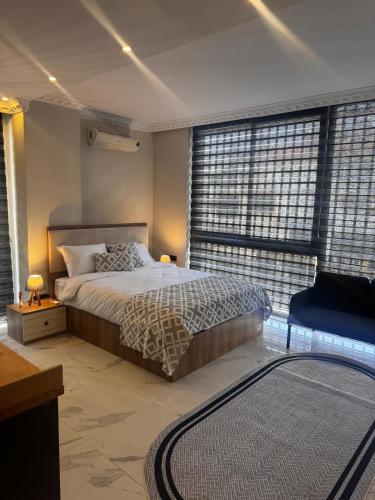 a bedroom with a bed and a chair and windows at The Rooms Lara in Antalya