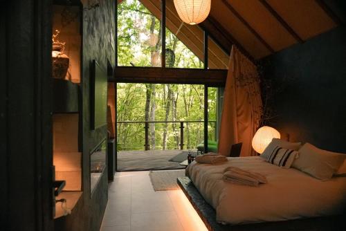 a bedroom with a bed and a large window at Domaine Wabi sabi lodge - 2 lodges d'exception - forêt in Turenne