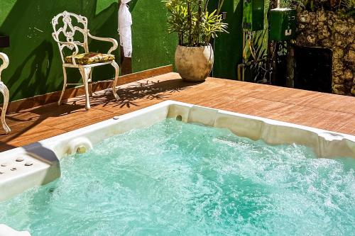 a hot tub sitting on a deck with a chair at VELINN Pousada Recanto dos Tangaras in Juquei