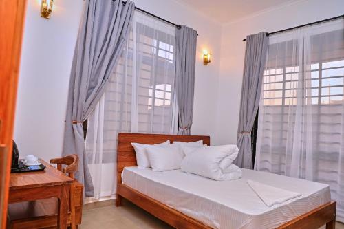 a bedroom with a bed and a desk and a window at Villa Maisha in Arusha