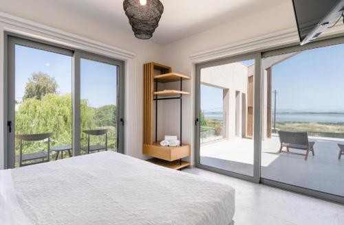 a bedroom with a large bed and large windows at The Retreat Villa in Lefkada