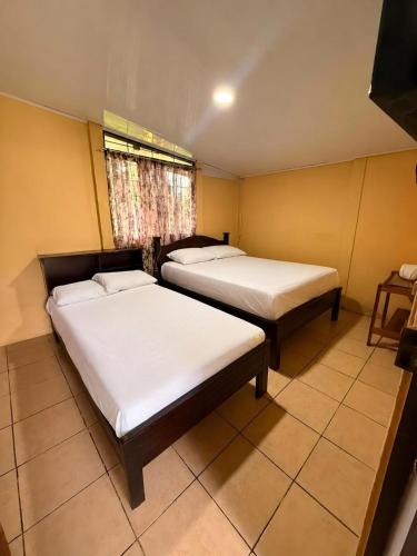 two beds in a small room with a window at Casa Colibrí Nature, Pool and Tranquility in Sarapiquí