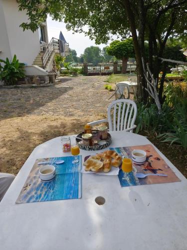 a white table with food and drinks on it at Les pieds dans l'eau Pergola in Fleurville
