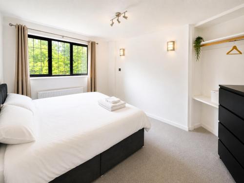 a white bedroom with a large bed and a window at Spacious 5-Bed Entire Home in Sherborne Saint John