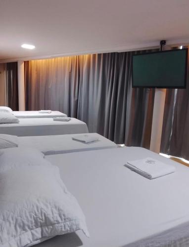a room with three beds and a flat screen tv at Chimarrão Hotel in Juazeiro