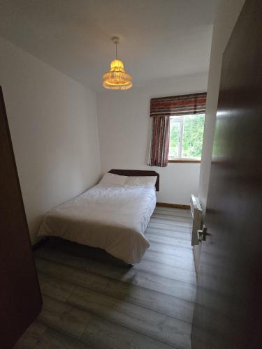 a bedroom with a bed and a window and a chandelier at The Garve Flats in Garve