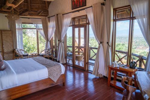 a bedroom with a bed and large windows at Maasai ecoLodge in Karatu