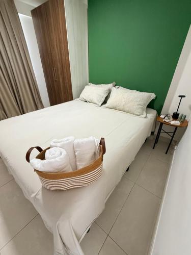 a white bed with a basket of towels on it at Studio 404 Premium Flat - Juazeiro do Norte - Cariri in Juazeiro do Norte