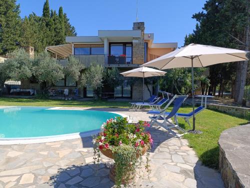 a swimming pool with two umbrellas and a house at Appartamento con piscina in Villa in Florence