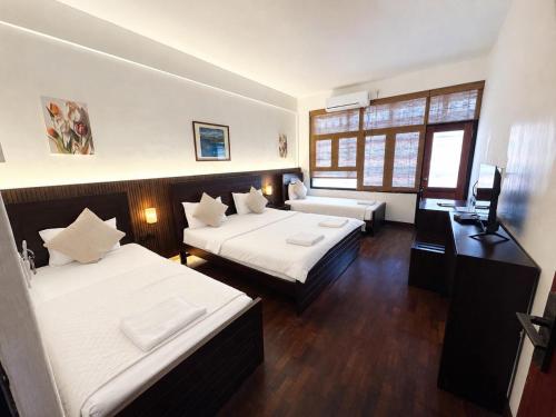 a hotel room with two beds and a television at Subhas Tourist Hotel in Jaffna