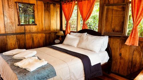 a bedroom with a bed with wooden walls and a window at Hostería los Cedros de Mindo in Mindo