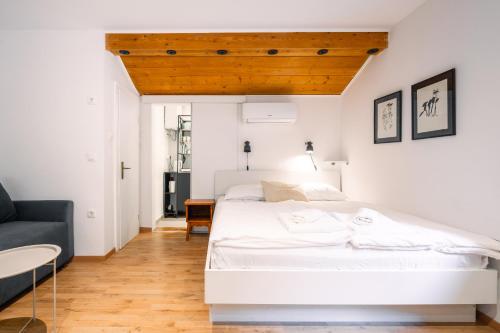 a bedroom with a white bed and a blue couch at Unique Forest Lodge Bled in Bled
