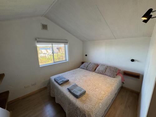a small bedroom with a bed and a window at Casa Miramar in Quellón