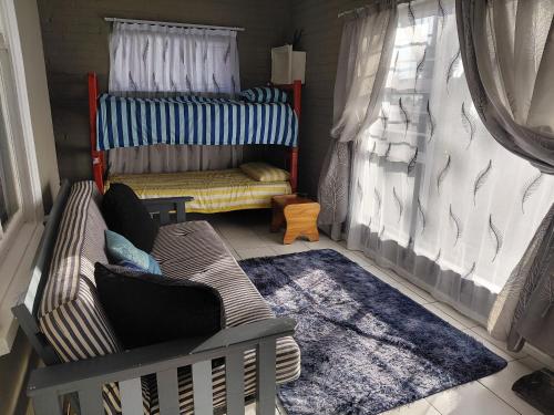 a room with a crib with a couch and a rug at Ocean River no 1 in Gqeberha