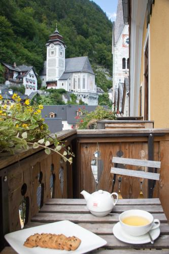 a table with a cup of coffee and cookies on a balcony at Seehotel Grüner Baum in Hallstatt