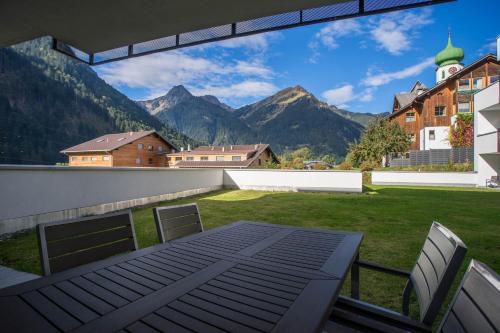 a patio with a table and chairs and mountains at Appart Gastauer in Sankt Gallenkirch