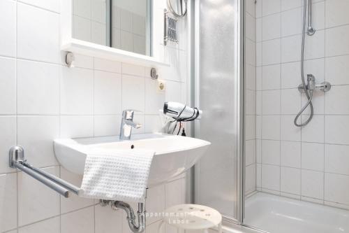 a white bathroom with a sink and a shower at Wiesenweg W10 in Laboe