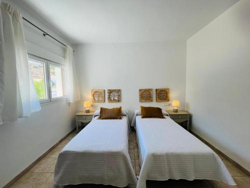 two beds in a room with white walls and a window at HOTEL MUSEO Lucainena in Lucainena de las Torres