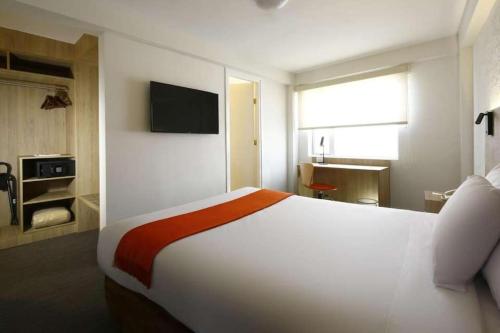 a bedroom with a large white bed and a television at Darios Hotel in Cusco