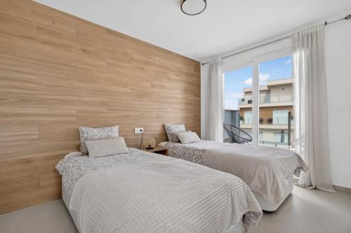 two beds in a room with a large window at Modern new Pool Villa in San Pedro del Pinatar