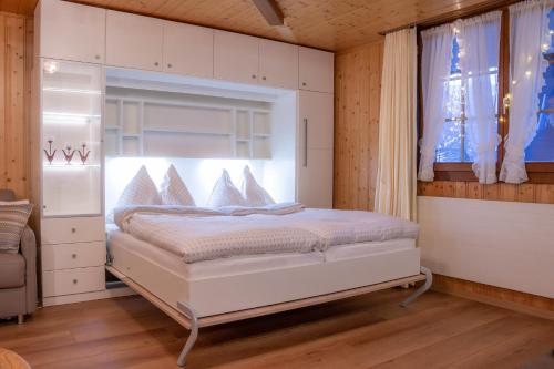 a bedroom with a white bed with a window at Chalet Heimetli in Grächen