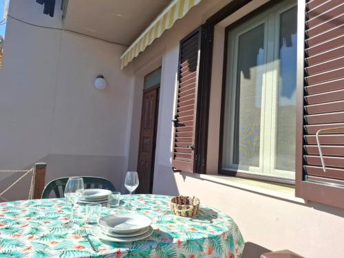 a table with plates and wine glasses on a balcony at Appartamenti L'Arcipelago in Marina di Campo