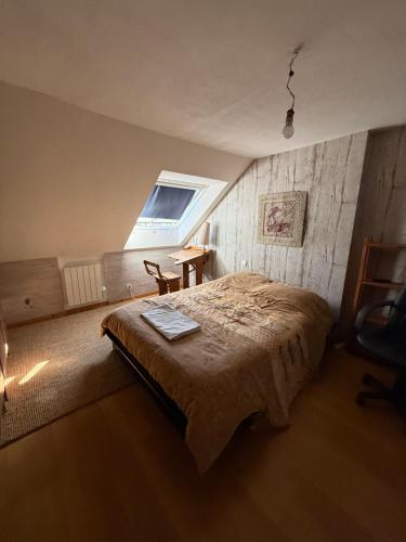 a bedroom with a bed and a window and a table at maison d'artiste chez Bé in Brunstatt