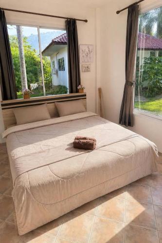 a large bed in a bedroom with a large window at Baan Sawang hidden in tropical calm in Ban Tai