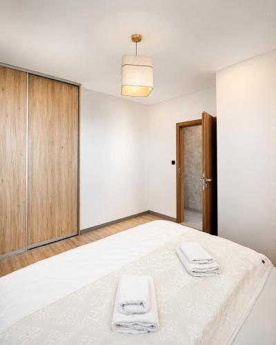 a white bedroom with a bed with two towels on it at Hotel Vibee Liptov in Liptovský Ján