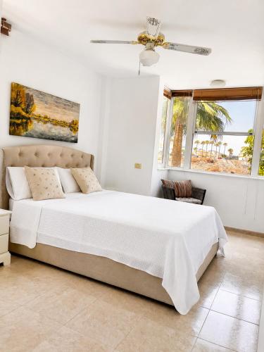 a white bedroom with a bed and a window at Tamaragua Apartment, Golf del Sur in San Miguel de Abona