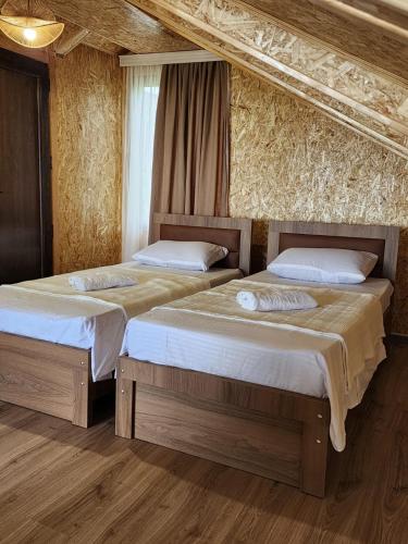 two beds in a room with wooden floors at Tsikhisdziri Panorama Cottage in Kobuleti