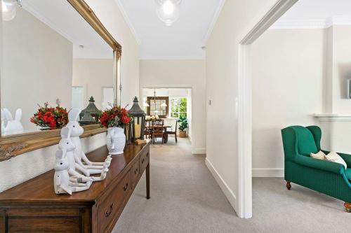 a living room with a mirror and a green chair at Stylish Apartment, Malvern East in Melbourne