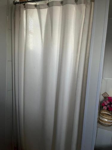 a white shower curtain in a bathroom at Hospedajes CyC in Llanquihue