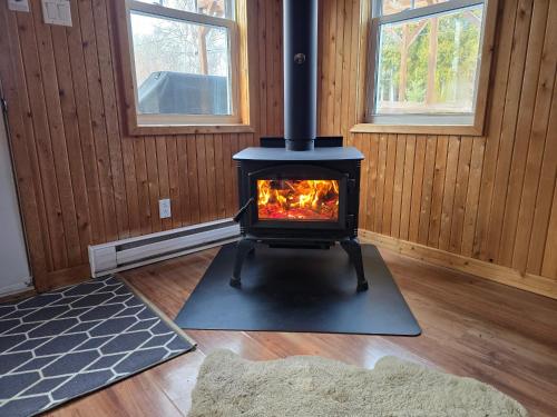 a stove in a room with wooden walls and windows at Chalets BSL in Saint-Simon-de-Rimouski